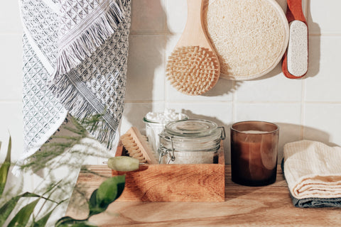 A variation of bamboo products including wash towel, scrubbing brushes and a container box sitting on a wooden surface.